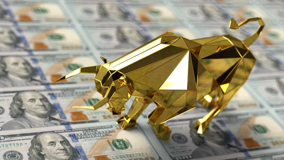 A golden bull stands on top of a slew of 100 US Dollar banknotes