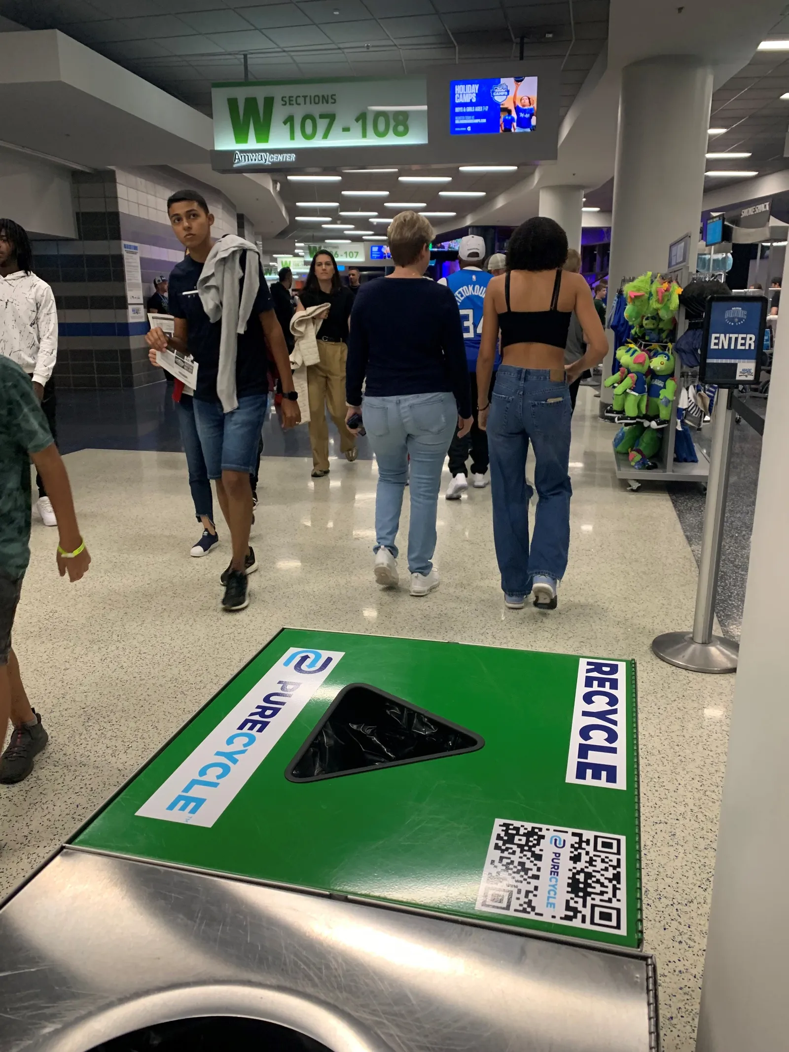 Crowd of people walking in background, recycling bin in foreground