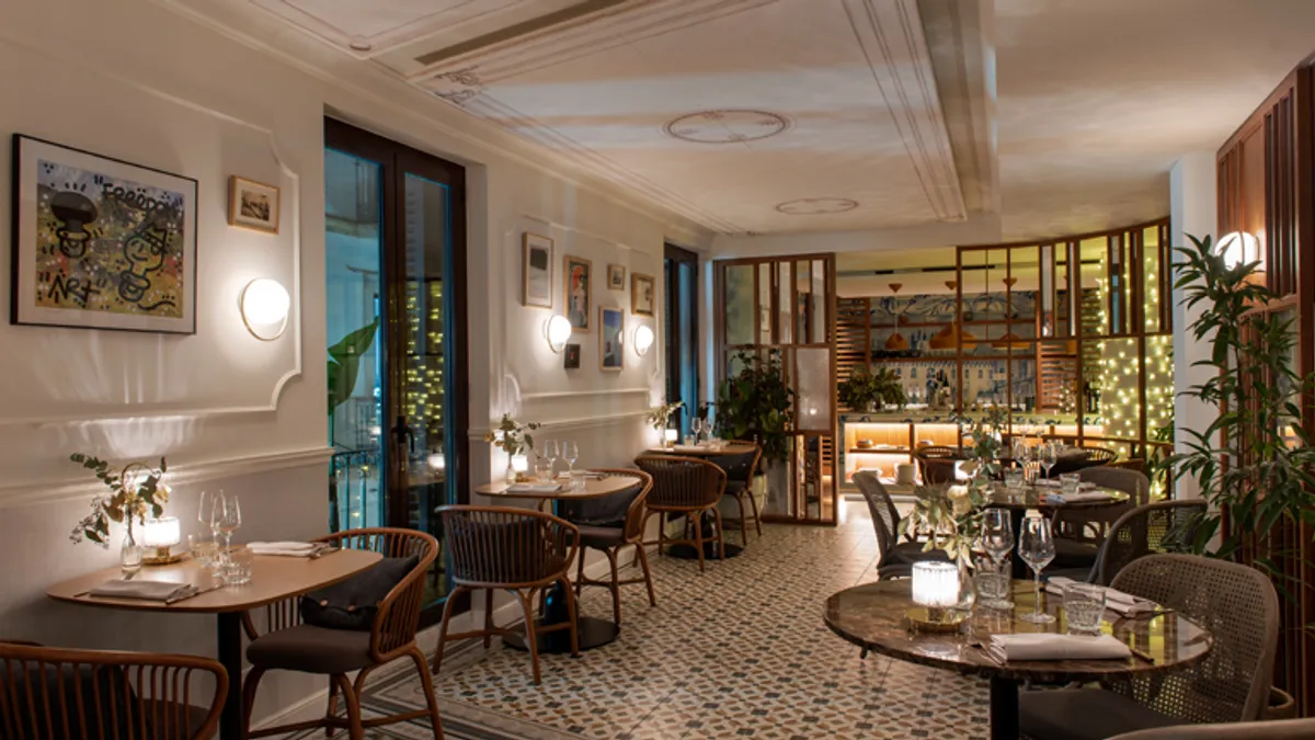 The interior at Fauna Restaurant shows wooden chairs, dim light and a tile floor.