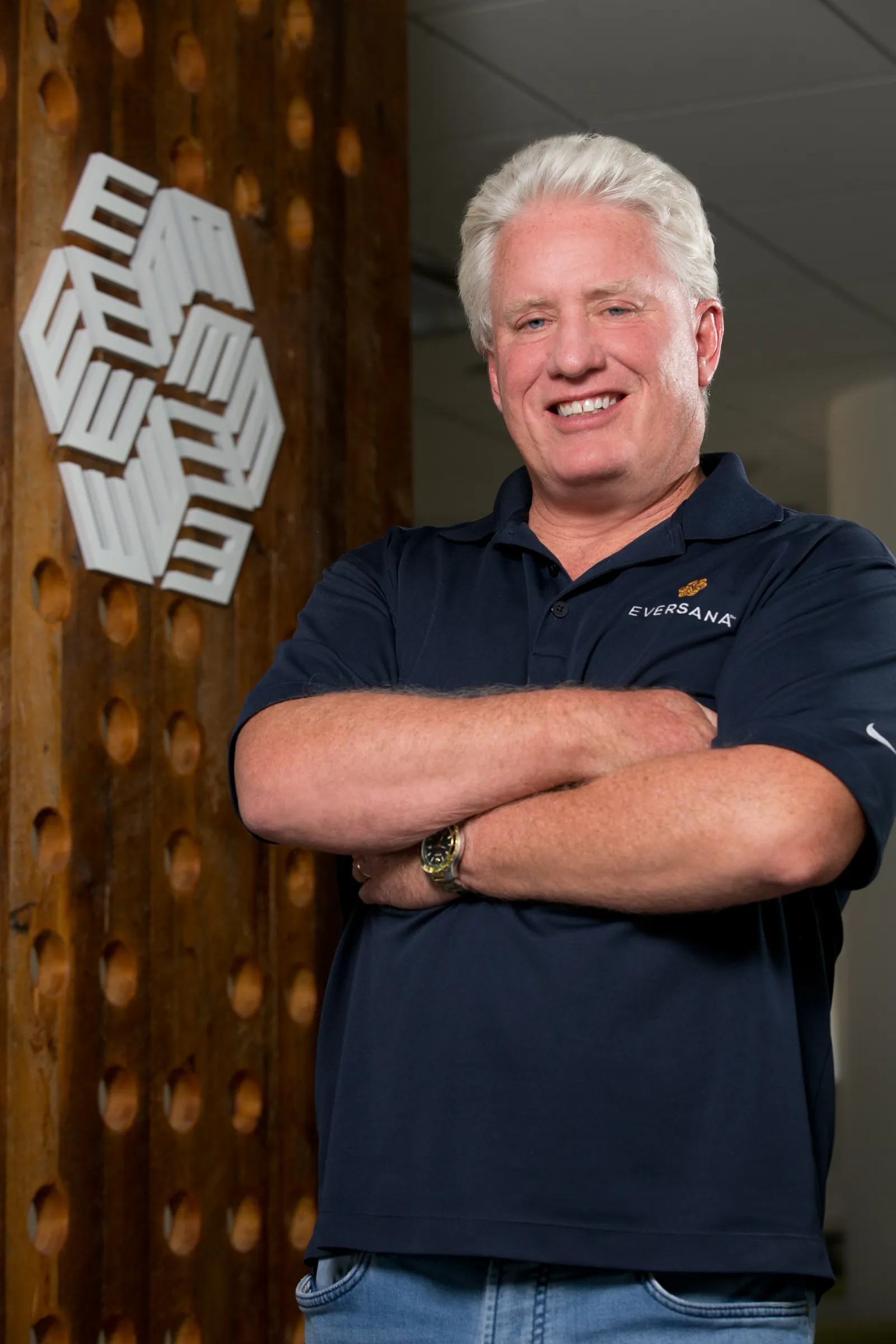 Jim Lang CEO of Eversana leaning against company logo