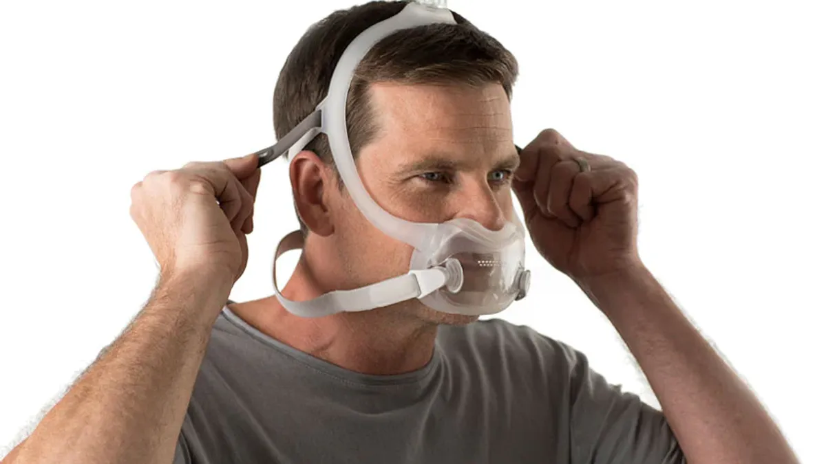 A man adjusting a Philips DreamWear sleep apnea mask