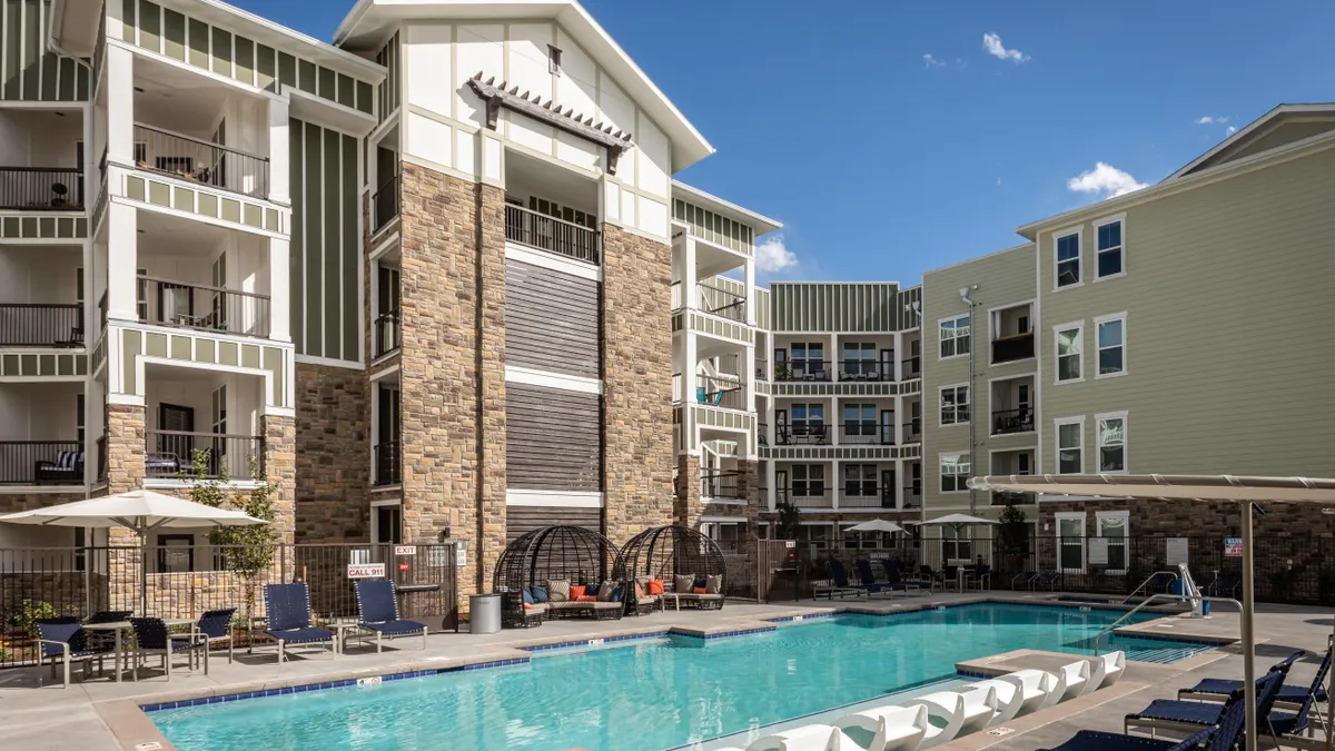 Brown four-story apartment building around a pool.