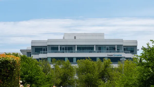 A building against a blue sky with trees and plants in front of it.