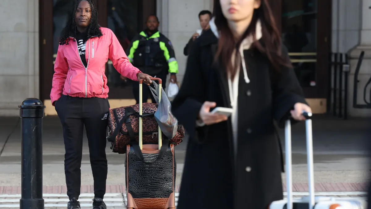 Travelers hold rolling suitcases.