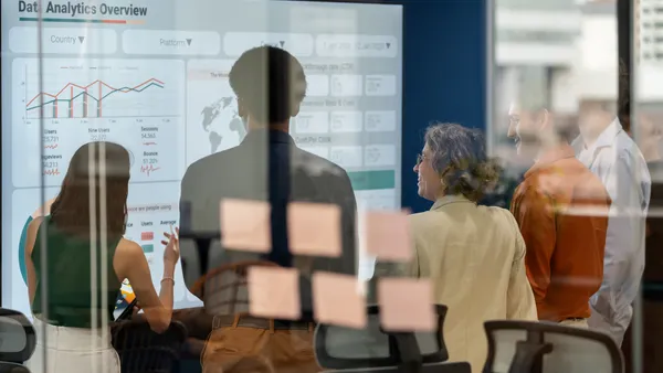 Diverse business development team brainstorming new products and services using a digital display during a business meeting.