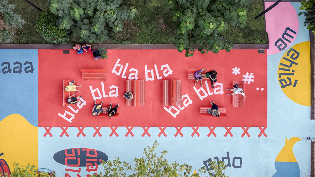 Aerial shot of colorfully painted plaza with people sitting on benches