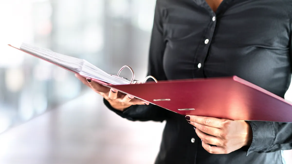 A person holds a three-ring binder open.