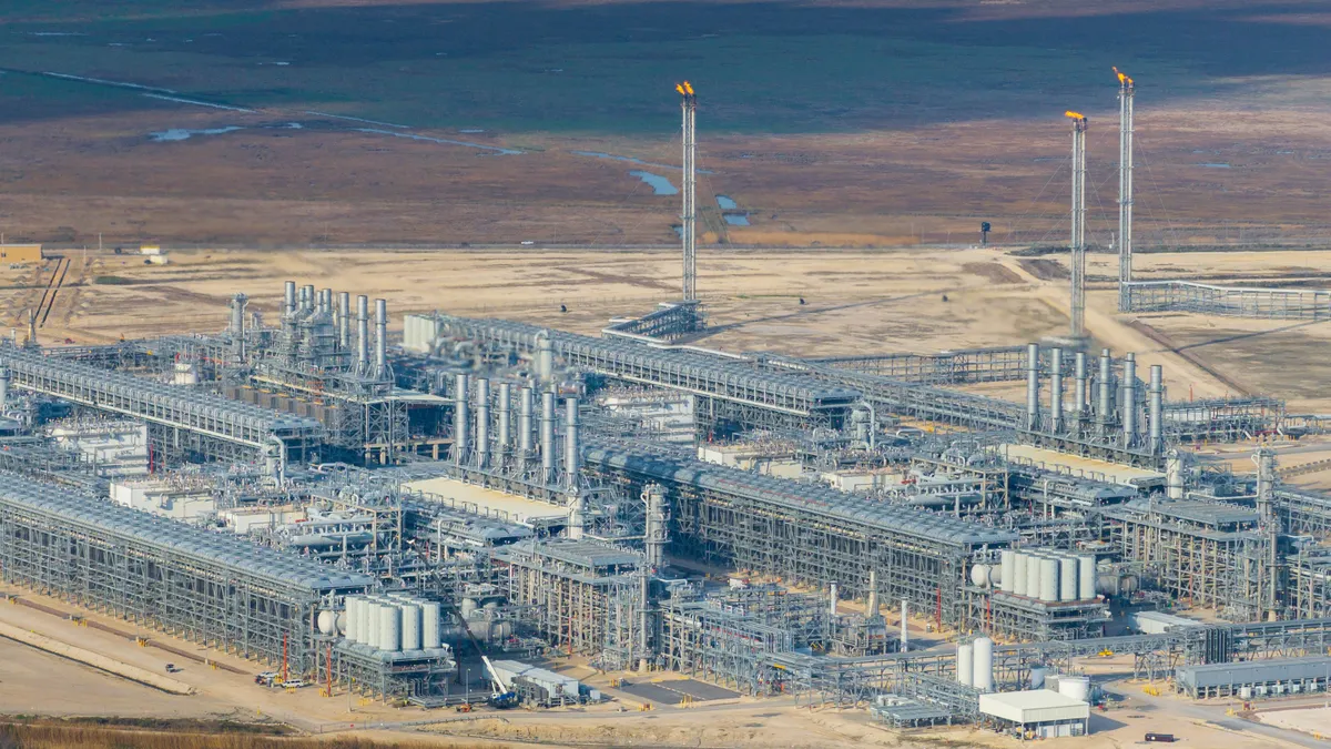 A sky-high view of a large collection of silver pipes in an arid region.