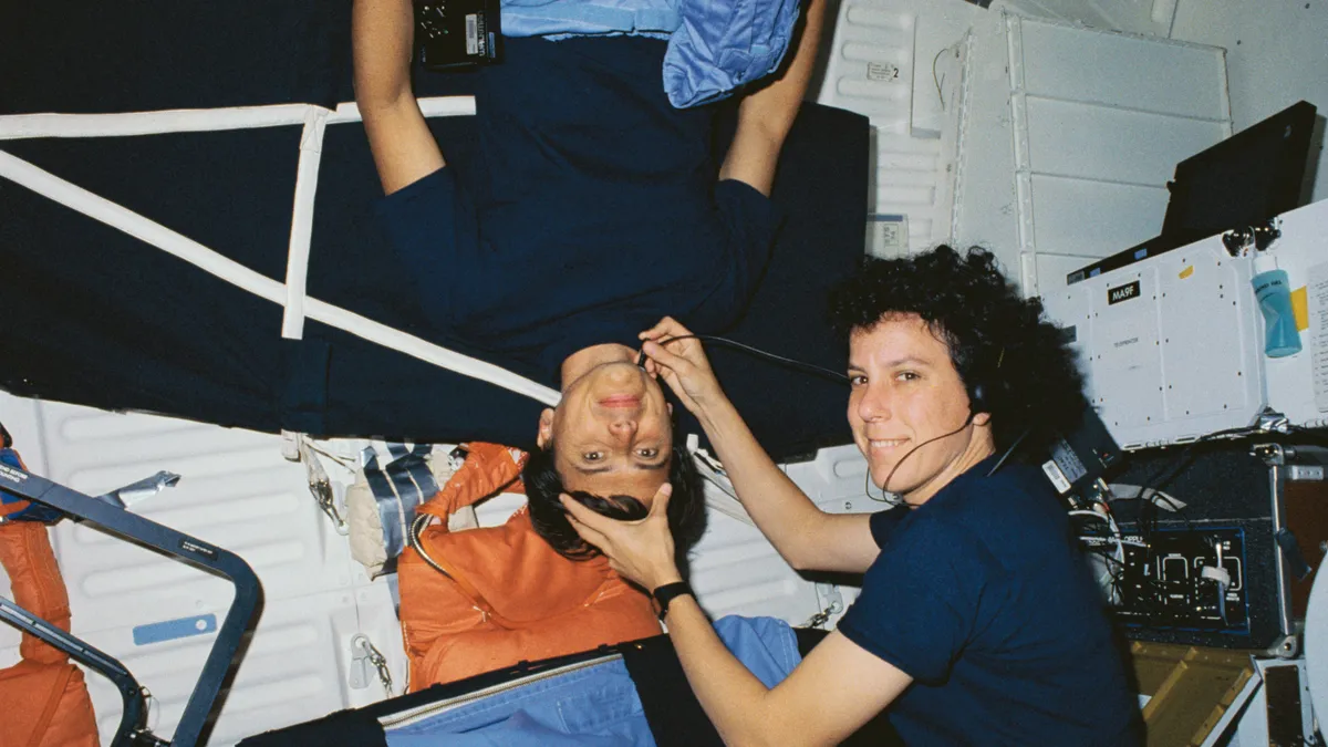 Astronaut performing medical examination on second astronaut