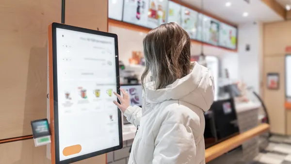 Person Using SelfService Kiosk in Modern Cafe.