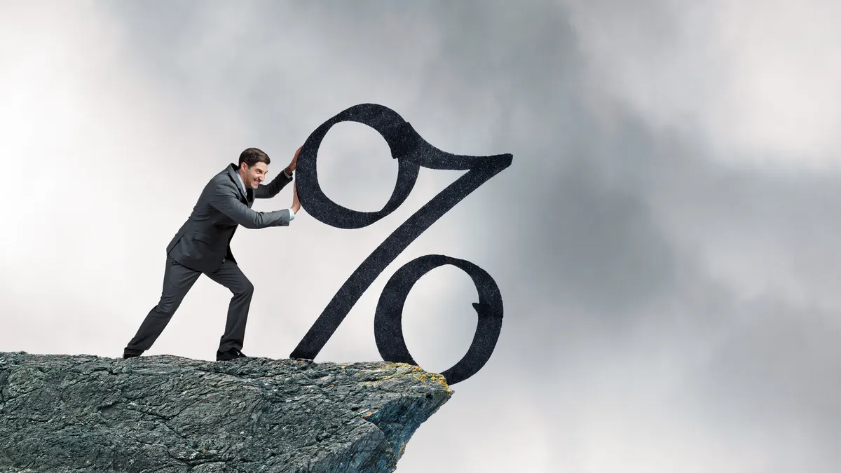 A businessman bushes a large percentage sing off the edge of a cliff.