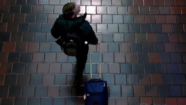 A person pulls a suitcase behind him.