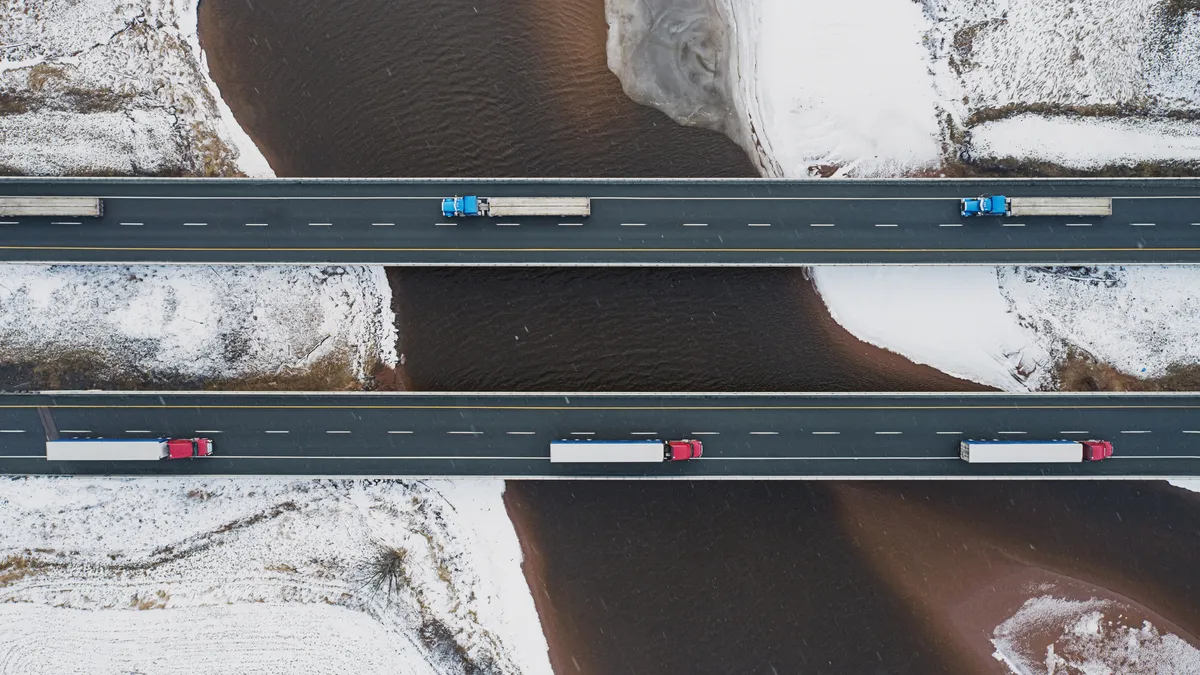 Aerial drone view of semi trucks crossing a tidal river.