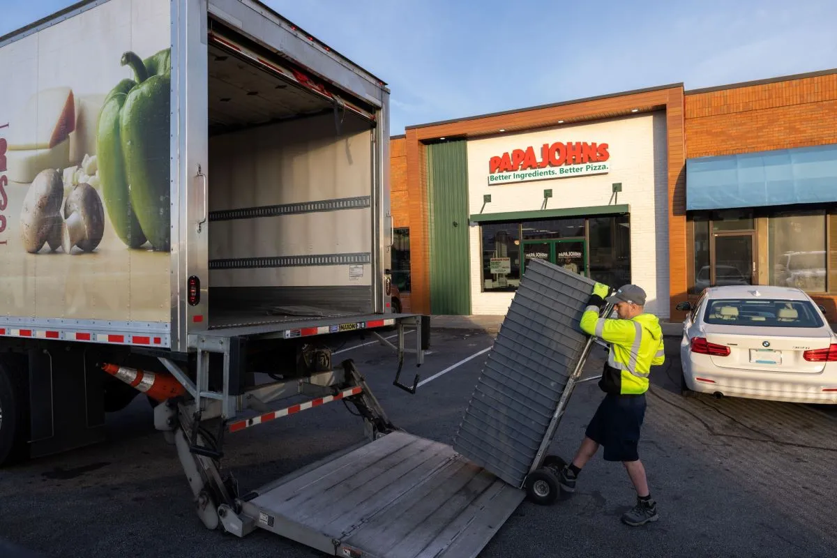 A Papa Johns worker delivers fresh dough and ingredients from a truck.