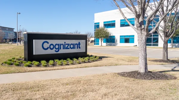 An office building in Plano, Texas with a sign emblazoned with the Cognizant company logo is pictured against a blue sky.