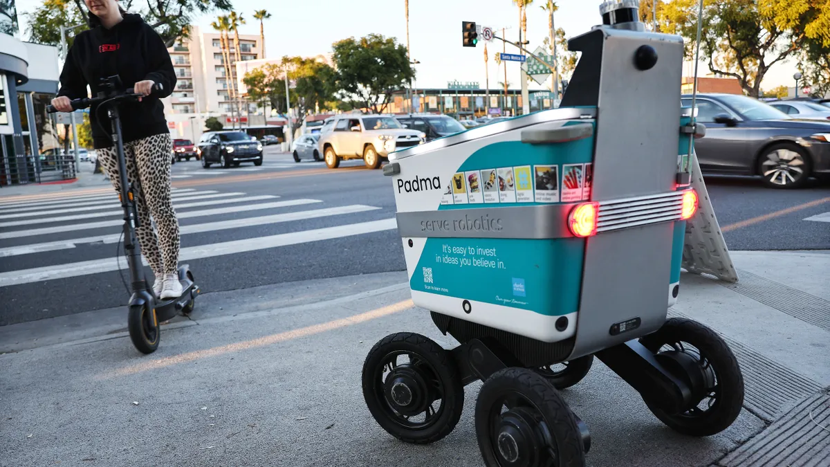 A delivery robot waits at a crosswalk.