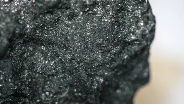 Dark gray graphite mineral sample under light microscopy.