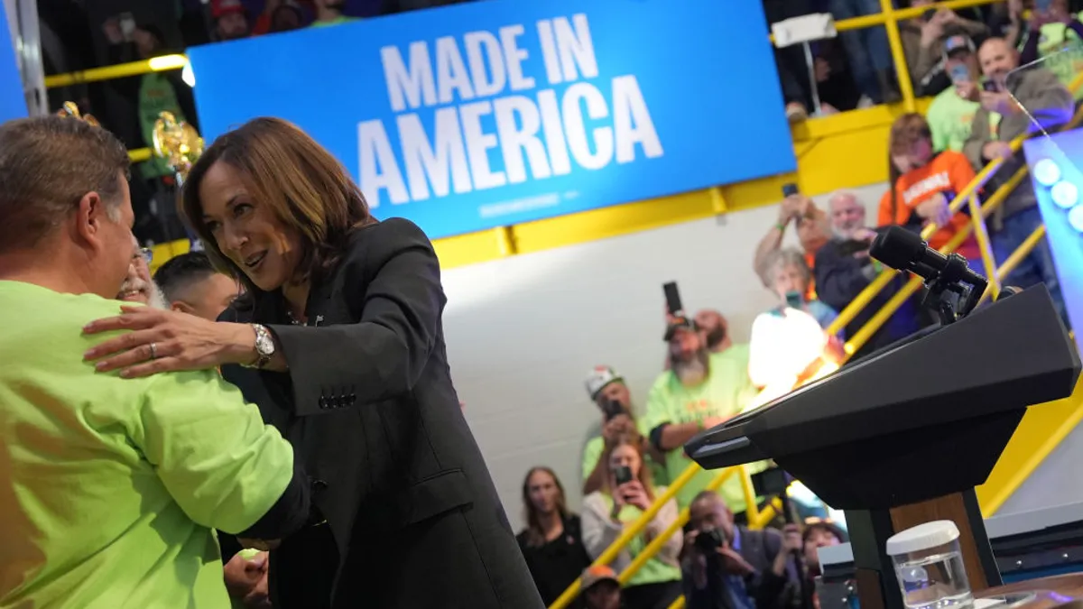 Kamala Harris greets a person in a bright yellow shirt at a campaign event.