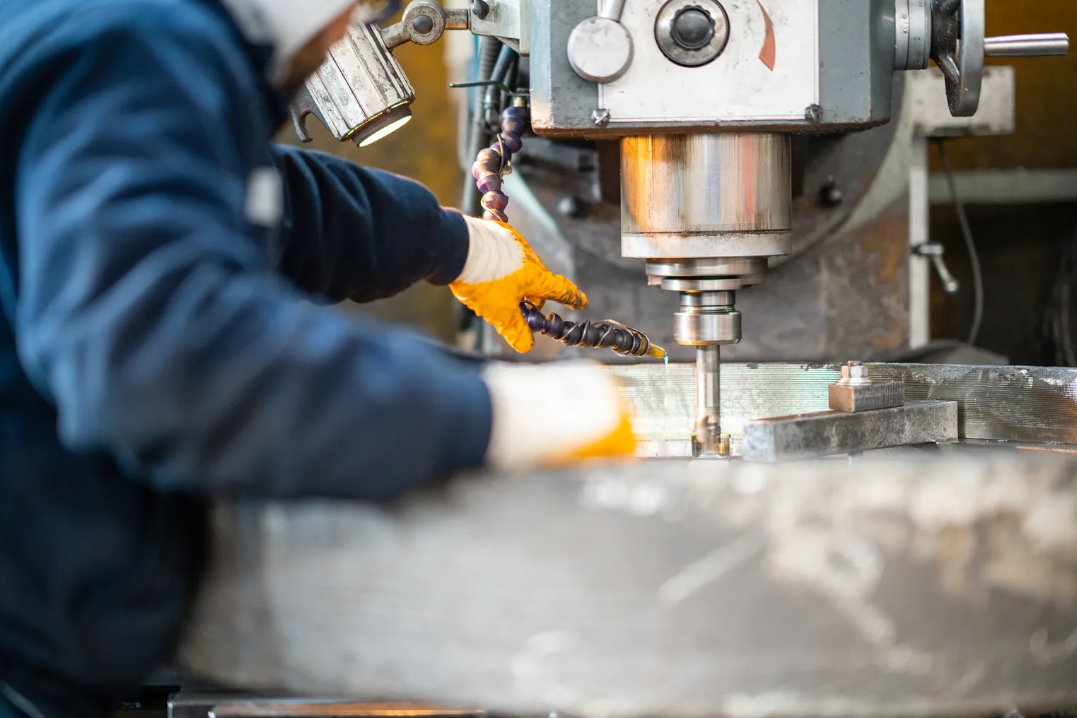 A worker in a factory uses a milling machine