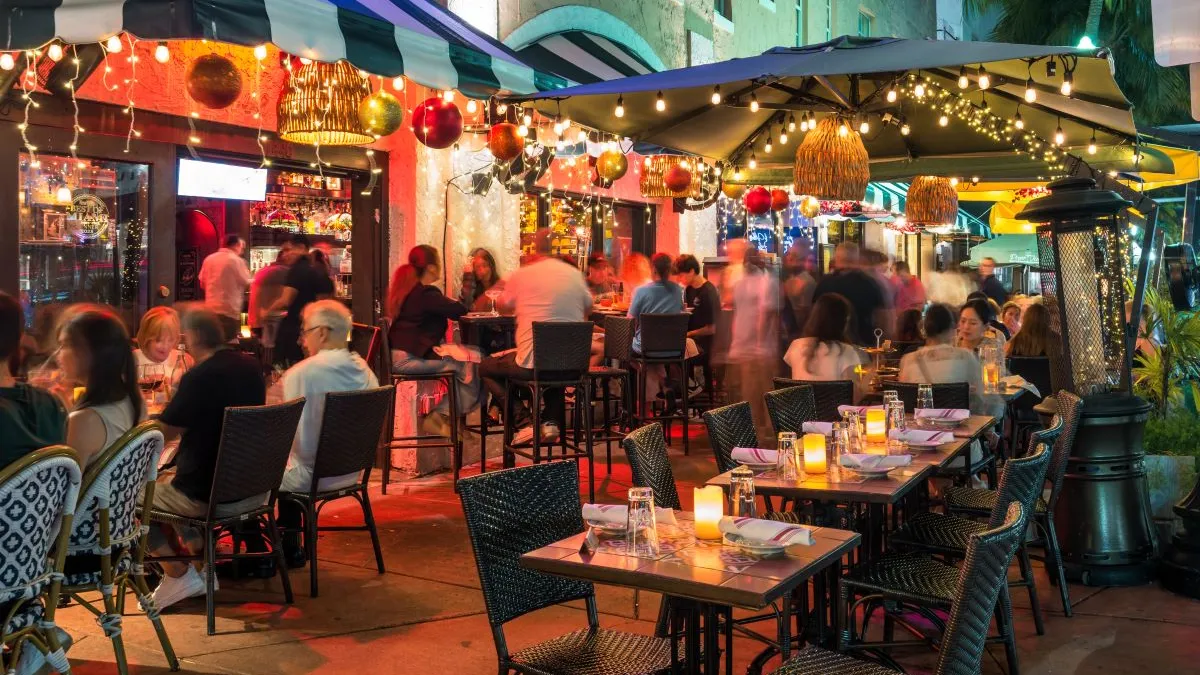 A night image of people sitting at tables at a patio in a restaurant