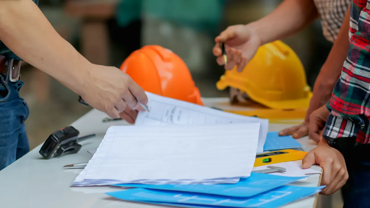 A group of construction workers look over documents in a meeting.