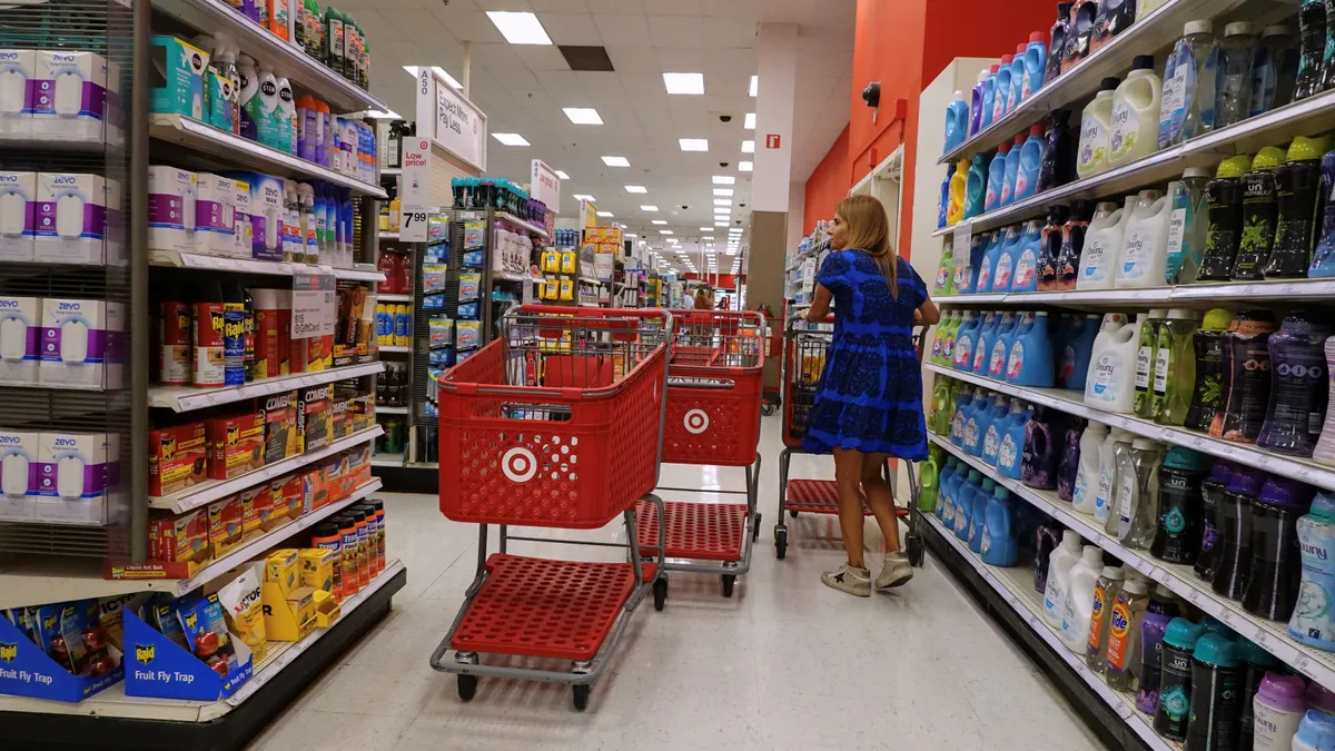 A person stands between shelves of items in a Target store with shopping carts