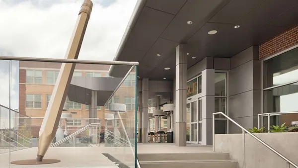 The exterior of a hotel features a large statue of a pencil.