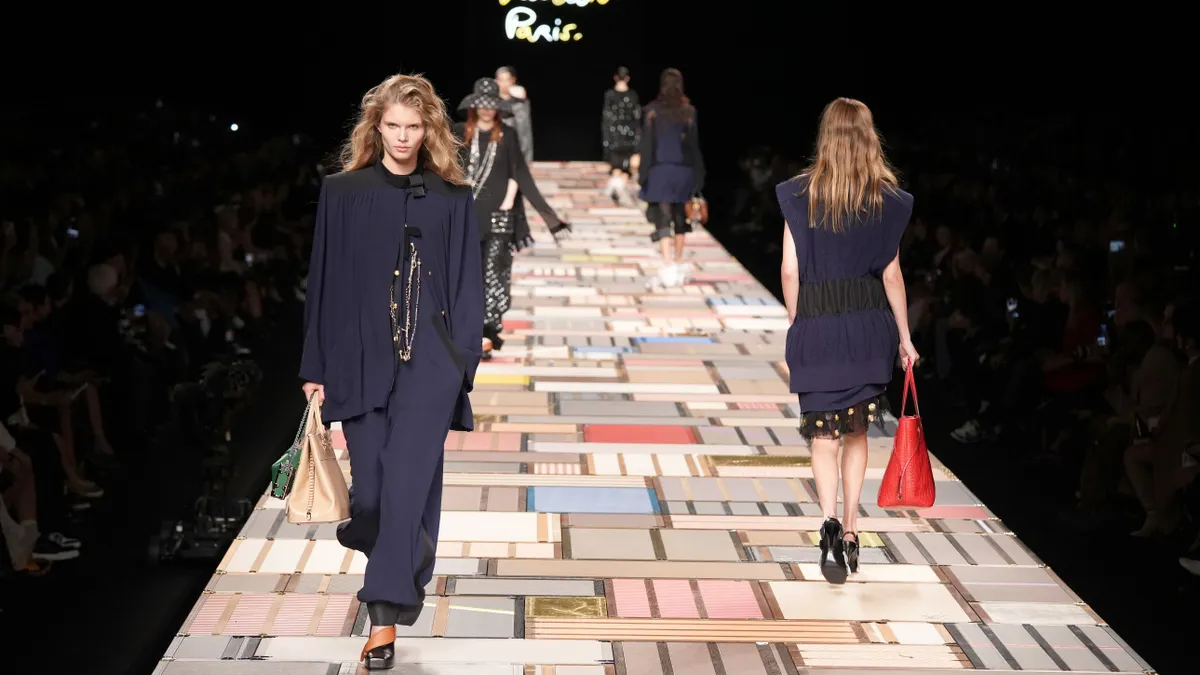 Models walk on a patchwork runway with the words Louis Vuitton Paris in the bacground.