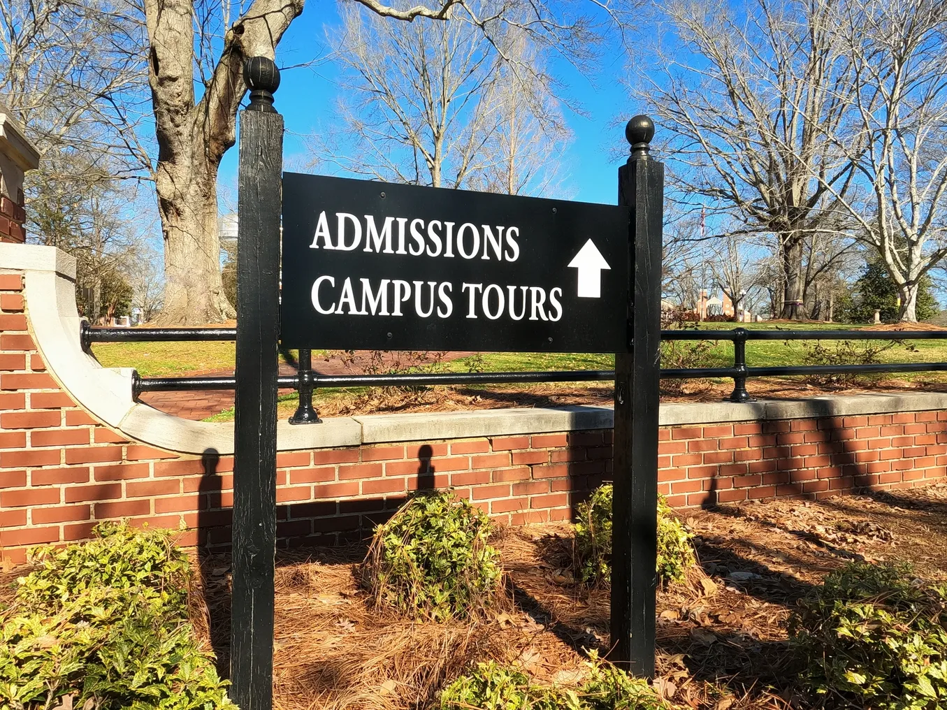 A sign points to a college admissions office.