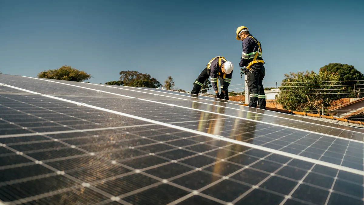 A pair of construction workers install solar panels