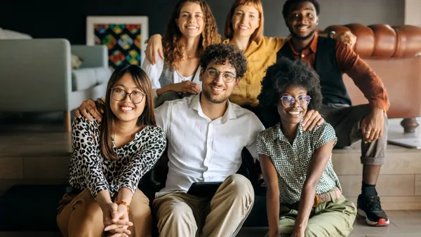 6 college students sitting on stairs, smiling, and close to each other