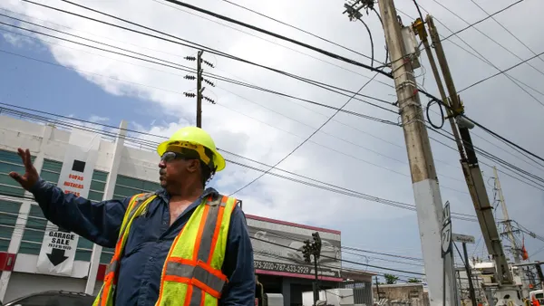A utility worker in Puerto Rico works to reconstruct the power grid after Hurricane Maria.