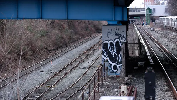 Railroad tracks with a subway train and station on the right.