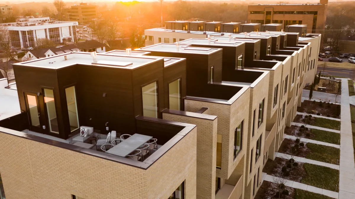 A row of townhomes backlit against the skyline.