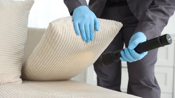A pest control technician inspects furniture.