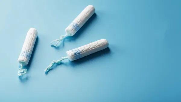 Three white gynecological tampons on a blue background.