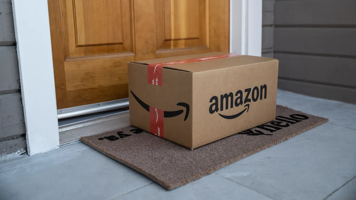 A large cardboard box sits on a welcome mat on the front porch of a house.