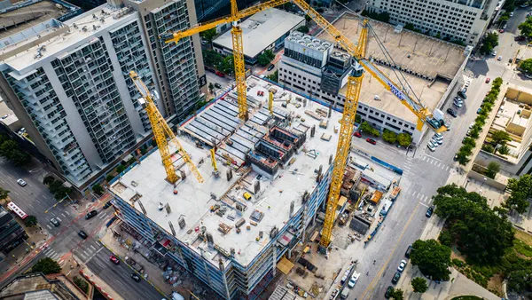 An aerial view shows cranes looming over a building under construction.