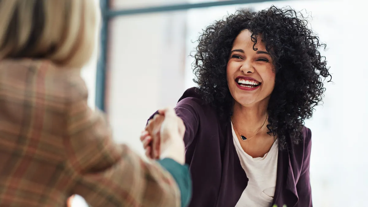 A new hire shakes a colleagues hand in the office