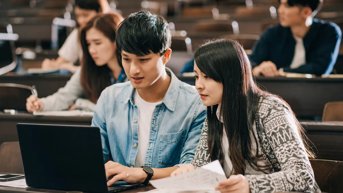 College students using a computer in a classroom.