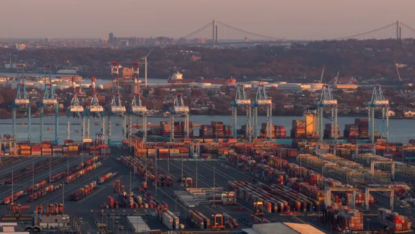 An aerial view of Port Newark-Elizabeth Marine Terminal at dusk with shipping containers, gantry cranes and shipping channels.