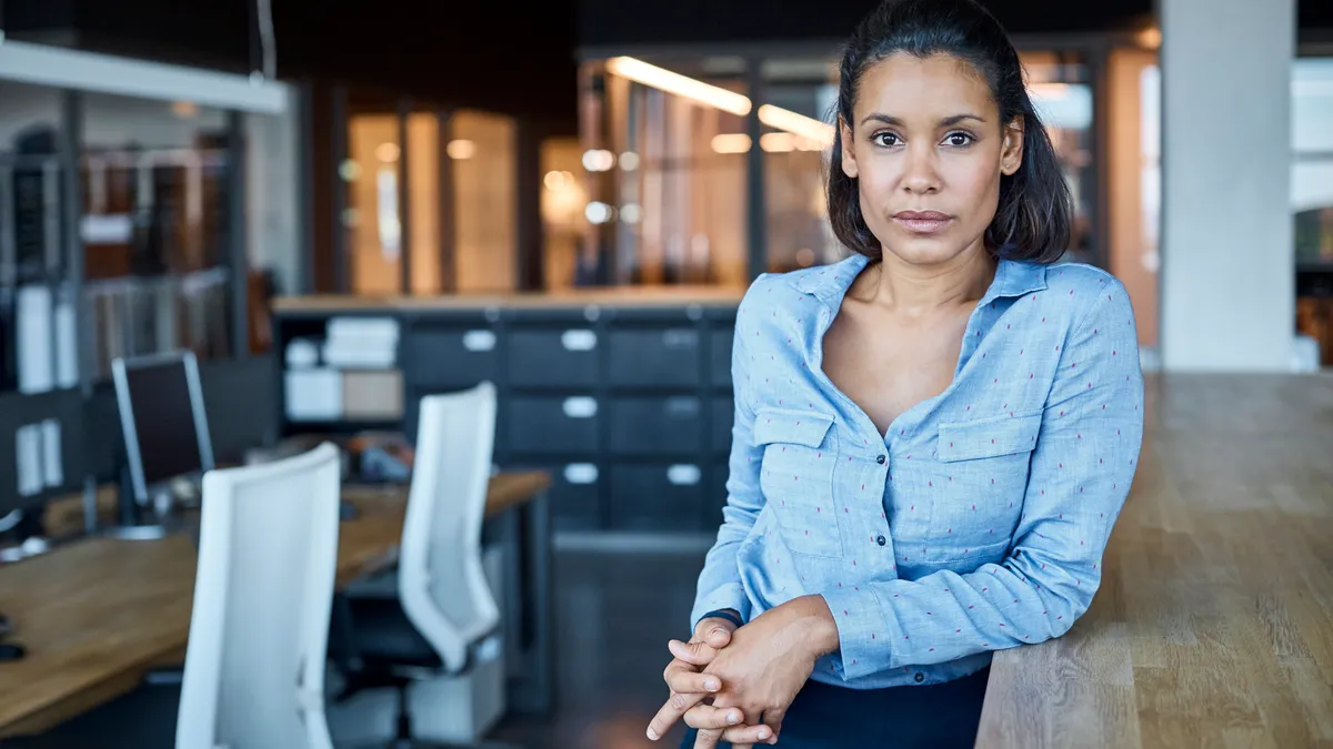 A brown person sits for a portrait at work