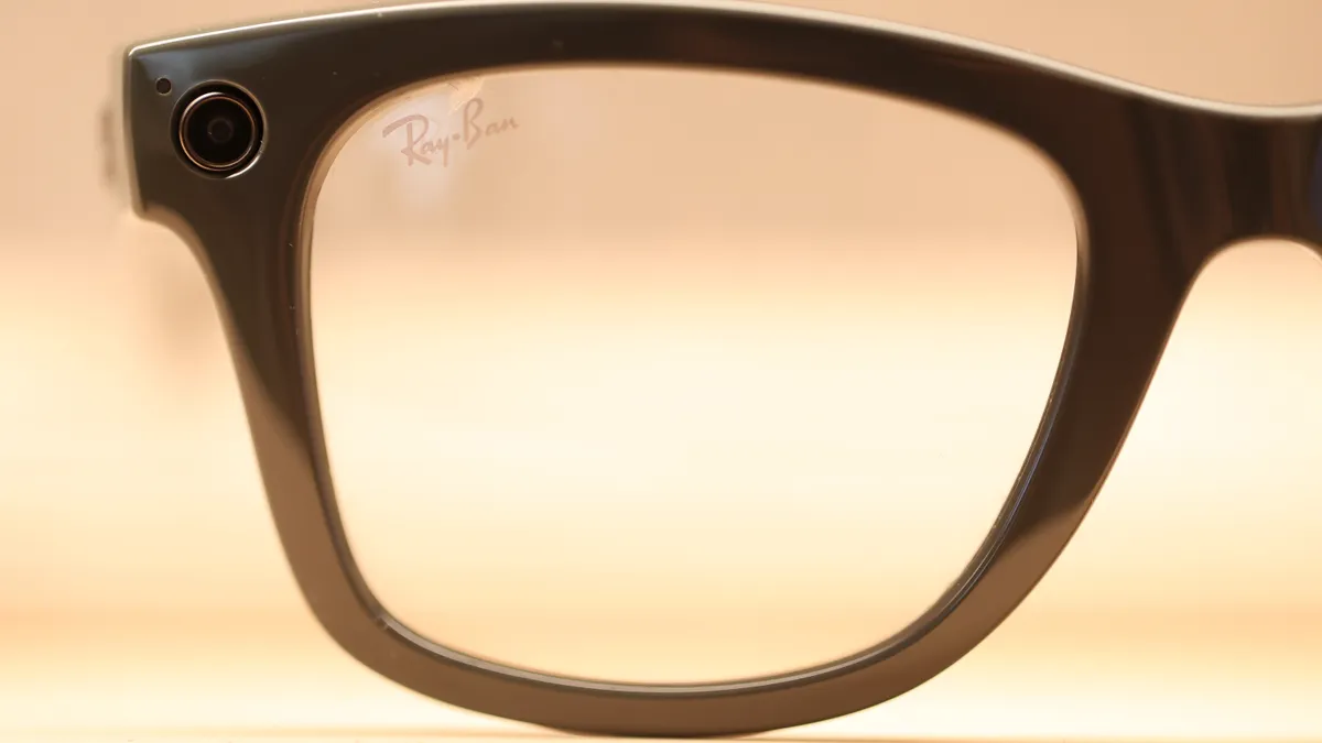 A pair of Ray-Ban branded sunglasses featuring a small camera embedded in the frame is seen in closeup.