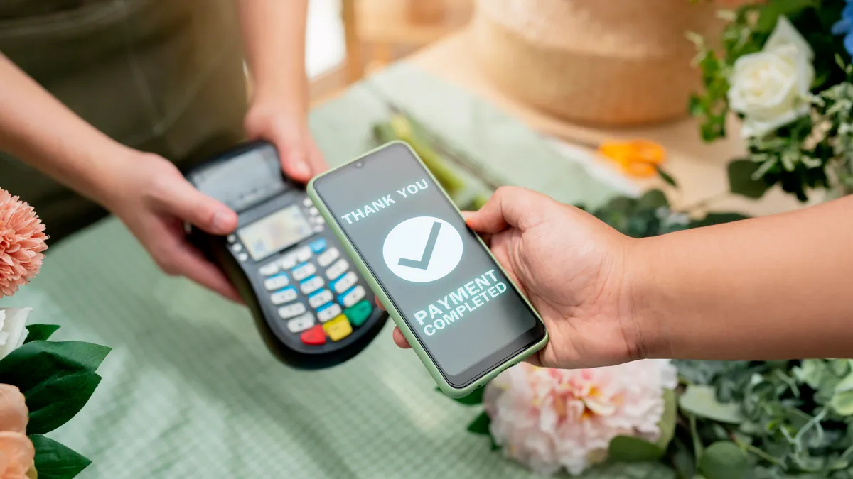 Close up of easy payment by credit card or smartphone application Greenhouse workers selling pottered flowers.