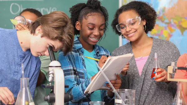 Junior high age school students conduct science experiments in classroom