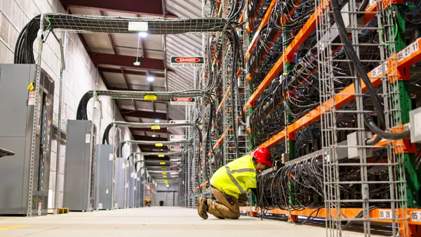 A man looks at data center wiring in a large warehouse.