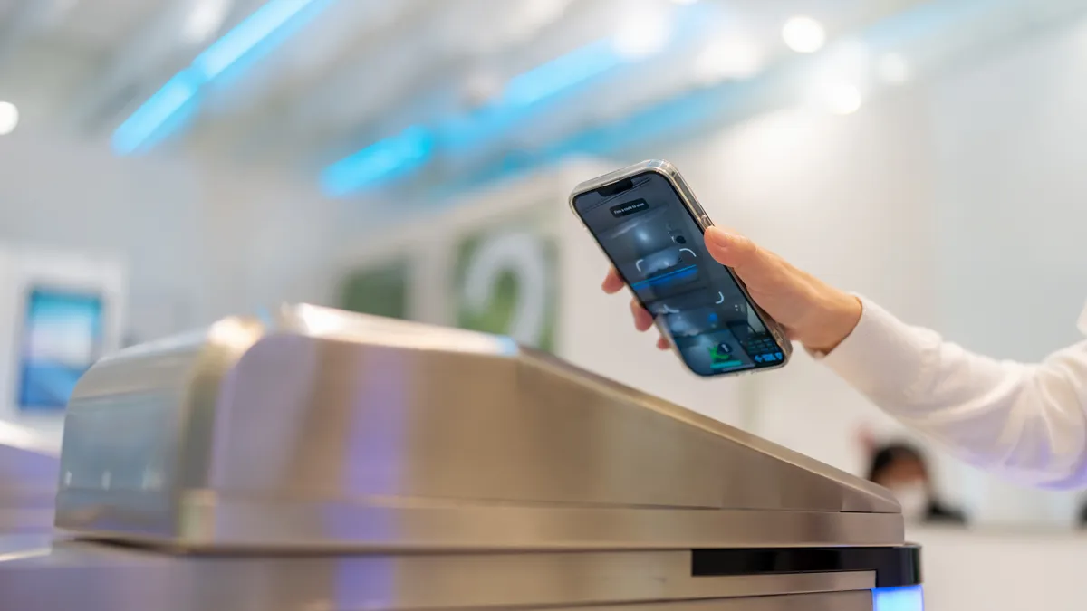 An employee aims their phone at an access control reader.