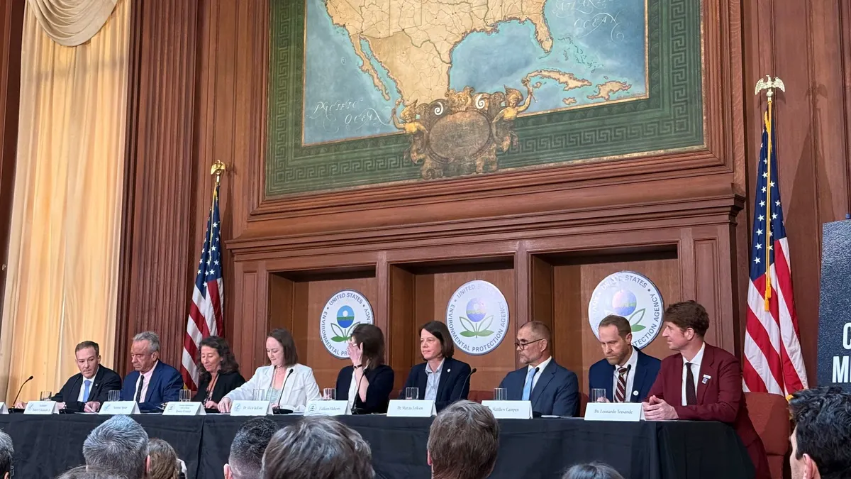 A line of speakers sit side by side underneath a decorative map