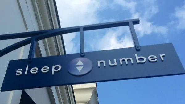 A sign juts out from the side of a building into a blue sky.