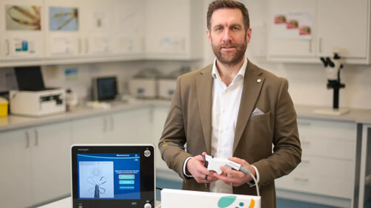 The CEO of Neurent Medical displays the Neuromark device with laboratory equipment in the background.